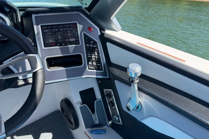 Slide: The Image of 2023 MasterCraft XT23 boat dashboard with modern controls and sleek design on a sunny day. - 16