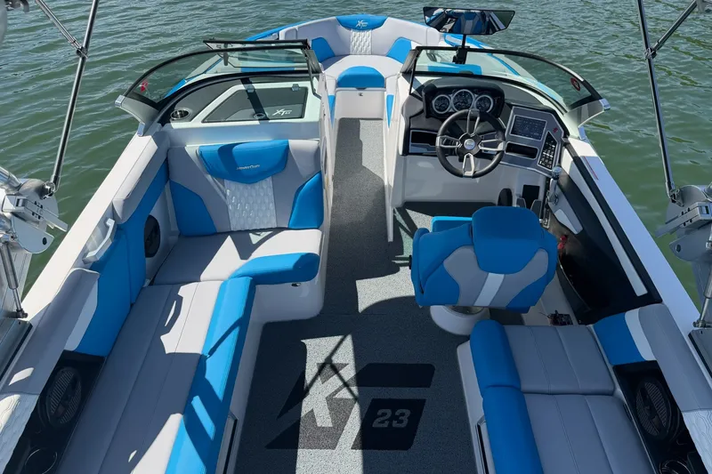 Slide: The Image of 2023 MasterCraft XT23 boat interior with blue and white seating on the water. - 23