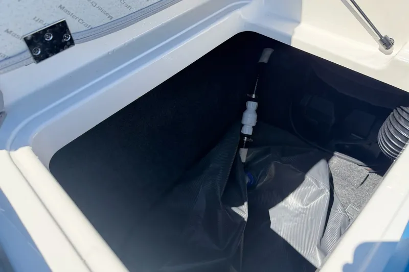 Slide: The Image of Storage compartment of 2023 MasterCraft XT23 boat, featuring interior components and tubing. - 34
