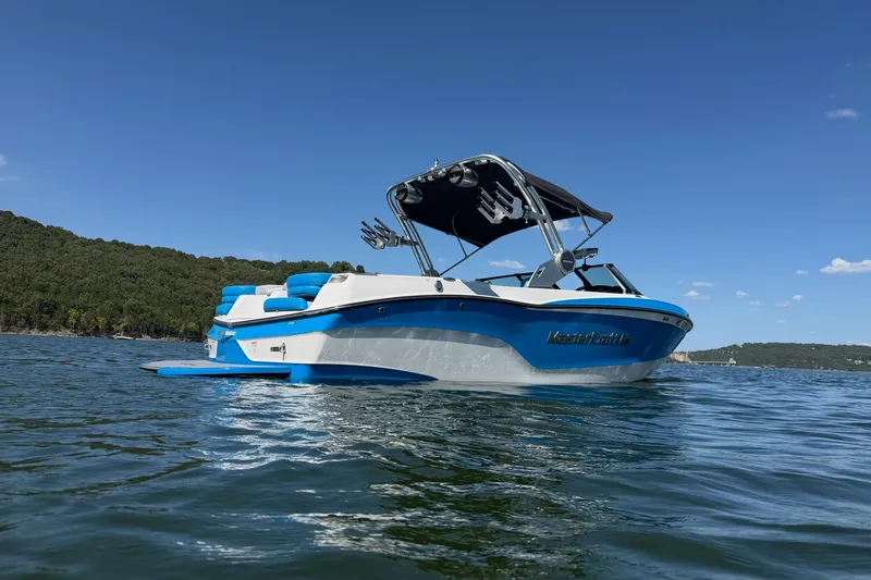 Slide: The Image of 2023 MasterCraft XT23 boat on a lake under clear blue skies. - 36