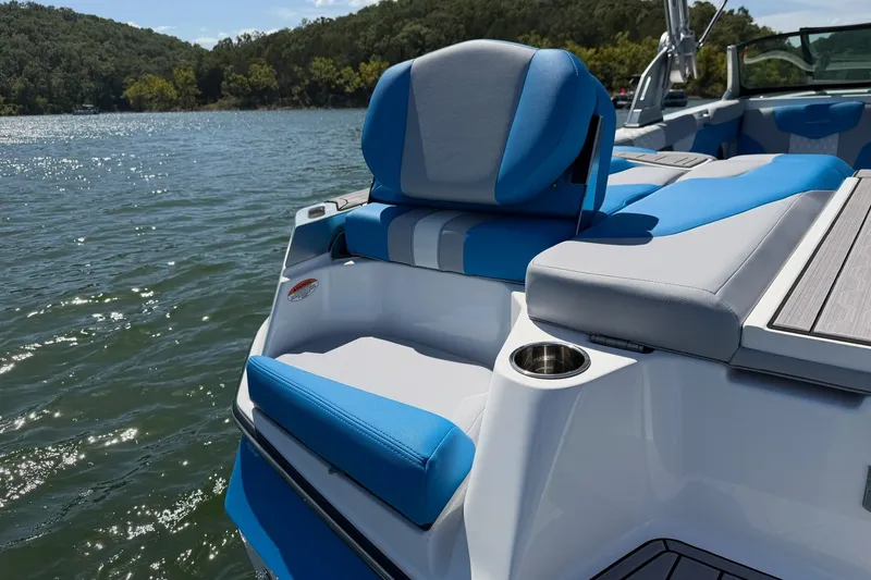 Slide: The Image of 2023 MasterCraft XT23 boat with blue and gray seating on a sunny lake. - 32