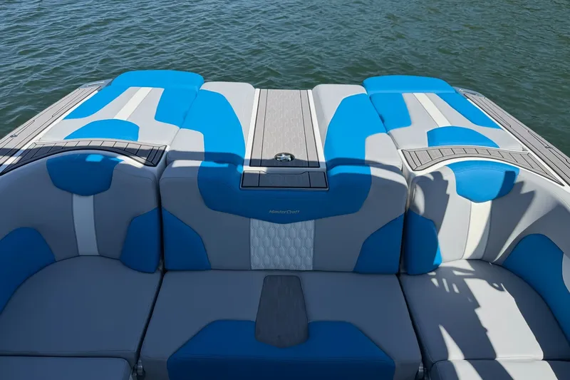 Slide: The Image of 2023 MasterCraft XT23 boat interior with blue and gray seating on the water. - 25