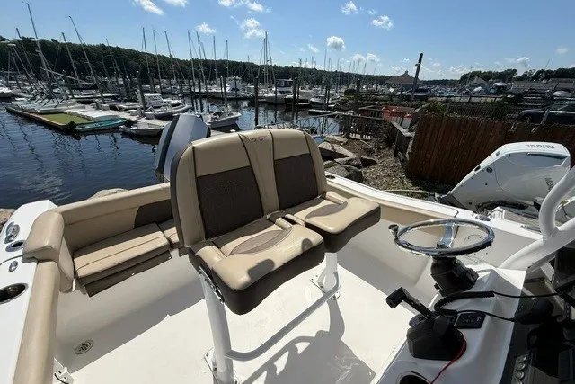 Slide: The Image of 2018 Tidewater 220 LXF boat interior with seating, docked at a marina under a clear sky. - 16