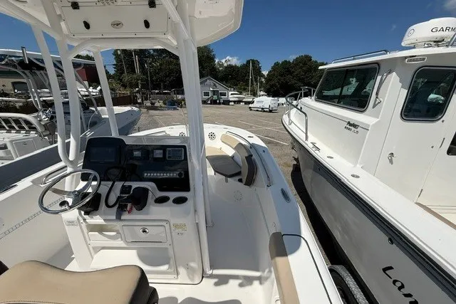Slide: The Image of 2018 Tidewater 220 LXF boat interior with console and seating, docked beside another vessel. - 11