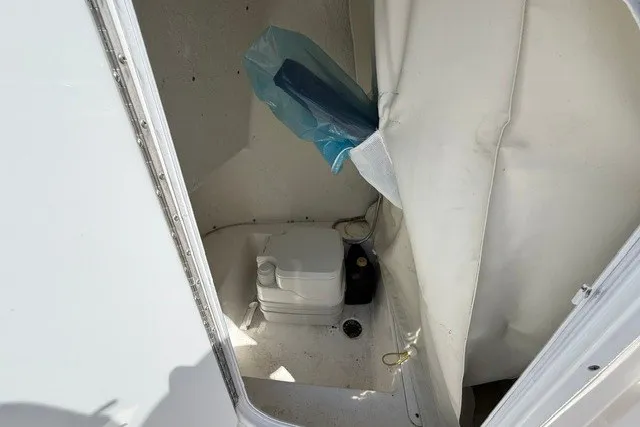Slide: The Image of Portable toilet inside 2018 Tidewater 220 LXF boat cabin, with storage and curtain. - 22