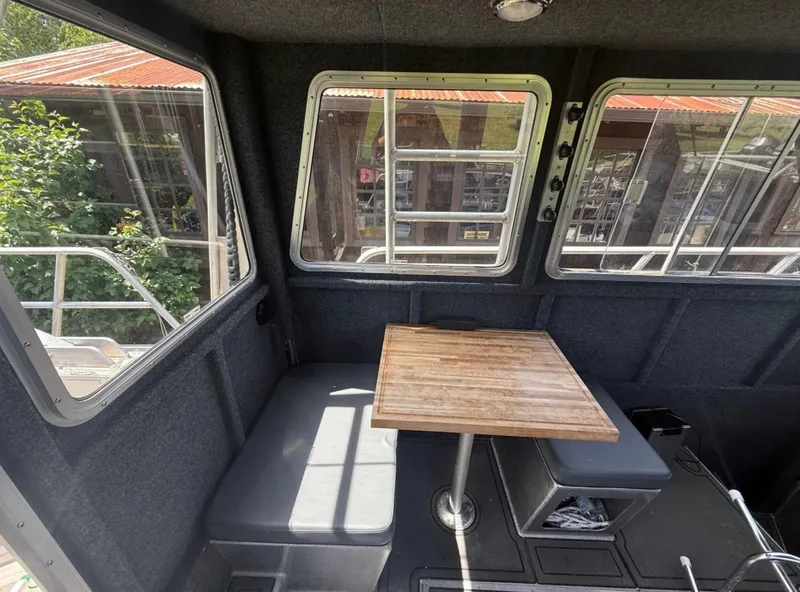 Slide: The Image of Interior of an aluminum patrol boat with a wooden table and cushioned seating. - 2