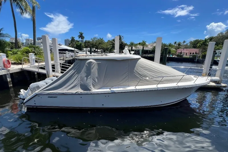 Slide: The Image of 2018 Pursuit OS 385 Offshore boat docked with cover, under clear blue sky. - 4