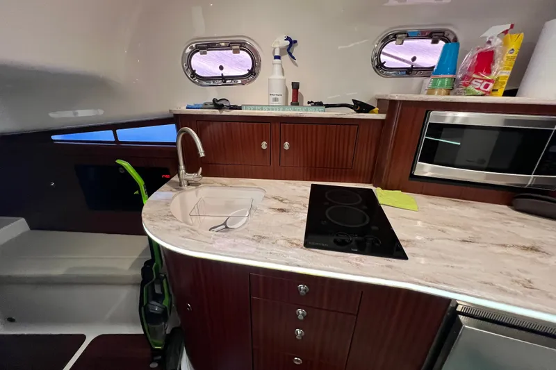Slide: The Image of 2018 Pursuit OS 385 Offshore yacht interior kitchen with stove, sink, and microwave. - 7