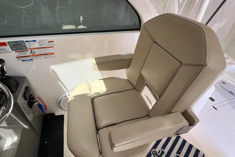Slide: The Image of Captain's chair on 2018 Pursuit OS 385 Offshore boat, featuring beige upholstery and armrests. - 21