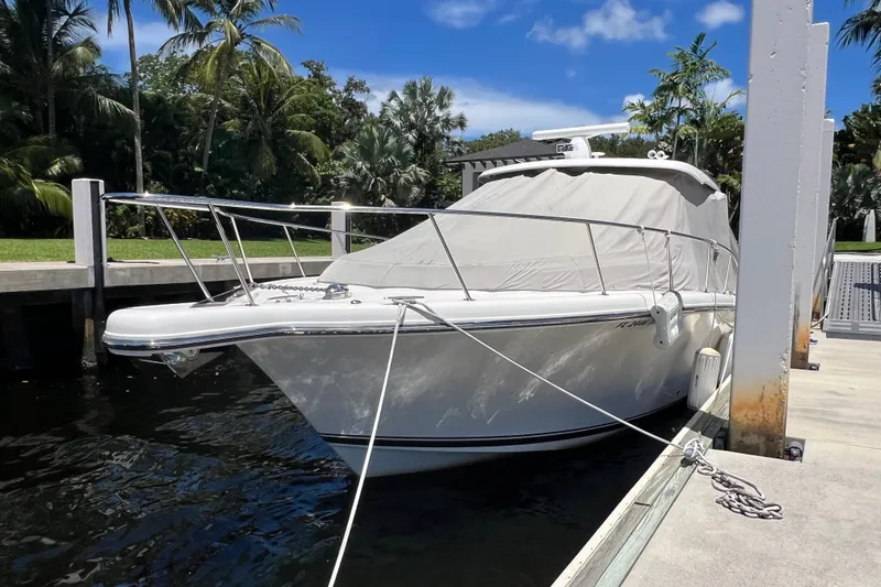 Slide: The Image of 2018 Pursuit OS 385 Offshore boat docked, covered, surrounded by tropical trees. - 3