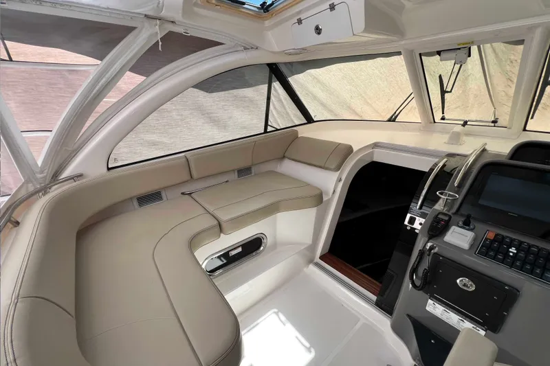 Slide: The Image of 2018 Pursuit OS 385 Offshore boat interior with beige seating and modern cockpit controls. - 20