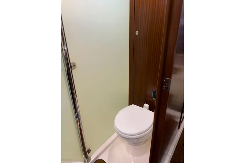 Slide: The Image of 2018 Pursuit OS 385 Offshore yacht bathroom with modern toilet and wooden paneling. - 21