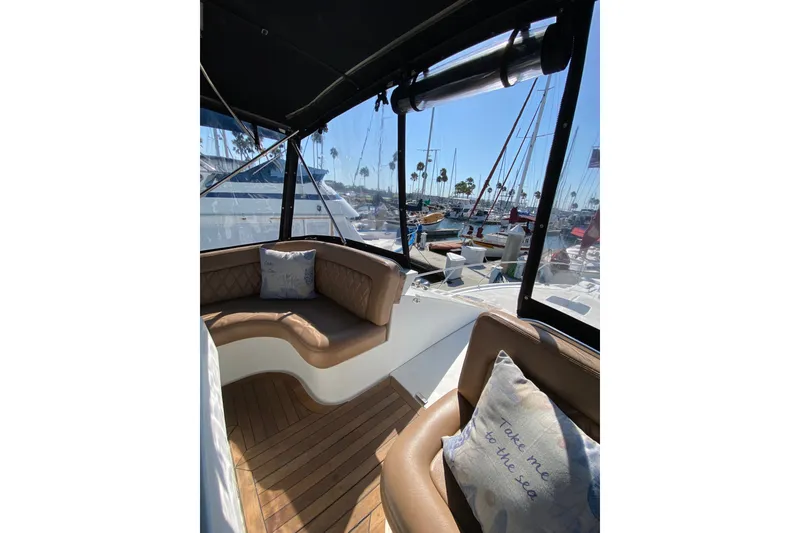 Slide: The Image of 1997 Mainship 40 Sedan Bridge interior with cushioned seating and marina view. - 25