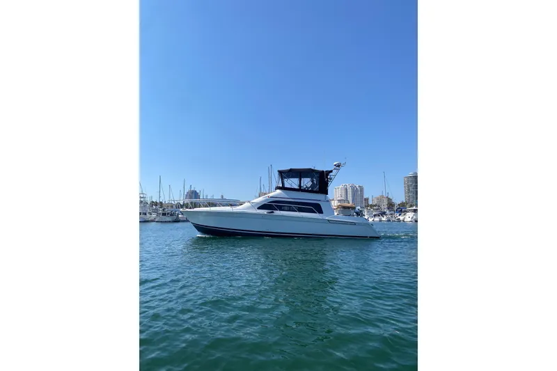 Slide: The Image of 1997 Mainship 40 Sedan Bridge yacht cruising in a marina under clear blue skies. - 16