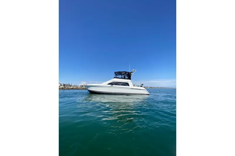 The Image of 1997 Mainship 40 Sedan Bridge yacht on calm blue water under clear sky. - 1