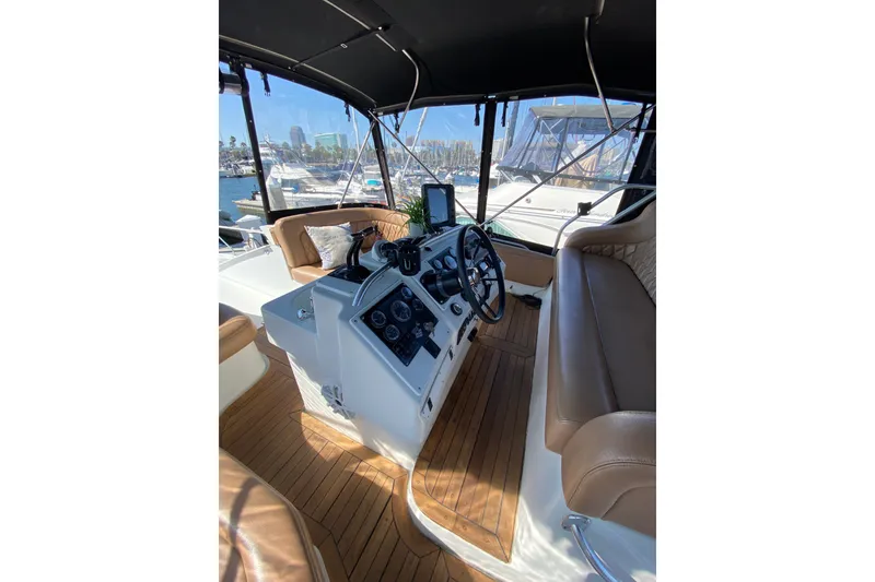 Slide: The Image of 1997 Mainship 40 Sedan Bridge helm with leather seating and modern controls, docked at marina. - 18