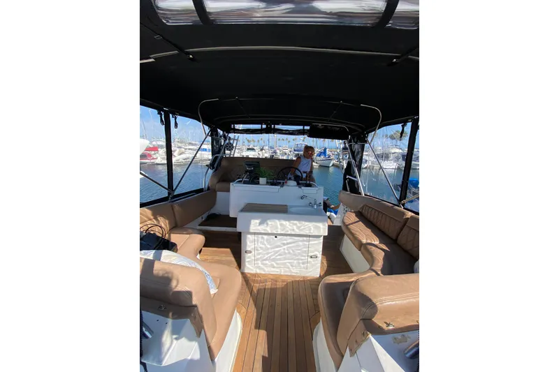 Slide: The Image of 1997 Mainship 40 Sedan Bridge interior with seating, helm, and marina view. - 26
