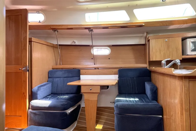 Slide: The Image of Interior of a 2004 Catalina 350 sailboat with wooden cabinetry and blue seating. - 7
