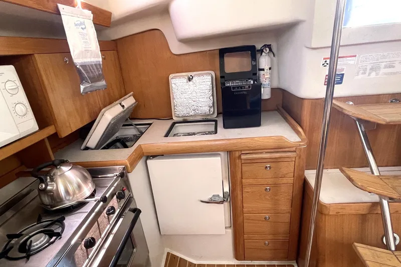 Slide: The Image of 2004 Catalina 350 yacht kitchen with stove, kettle, and wooden cabinetry. - 4