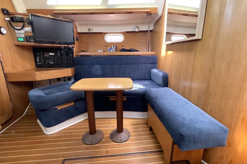 Slide: The Image of Interior of a 2004 Catalina 350 sailboat with blue seating and wooden table. - 6