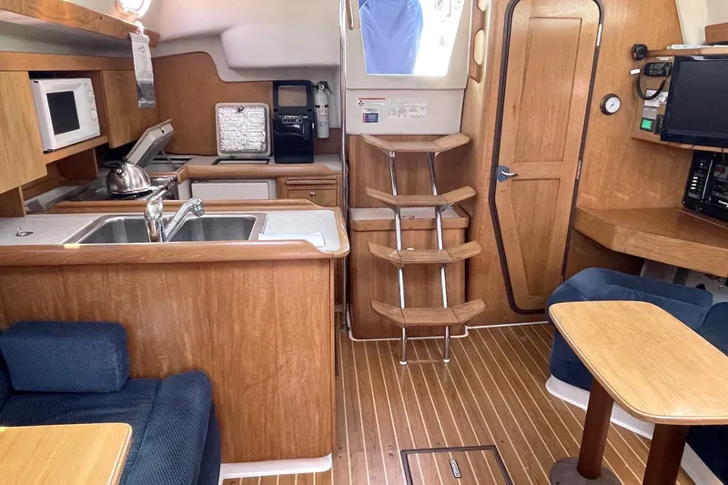 Slide: The Image of Interior of a 2004 Catalina 350 sailboat with kitchen and seating area. - 10