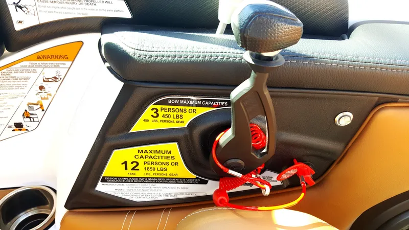Slide: The Image of Close-up of a 2017 Nautique Super Air Nautique 210 throttle lever with safety warnings. - 7