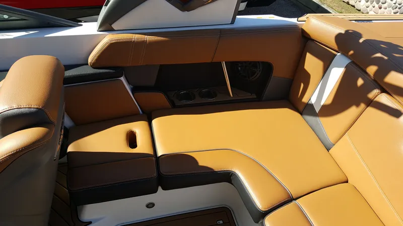 Slide: The Image of The interior of the 2017 Nautique Super Air Nautique 210 features brown upholstery and cup holders. - 10