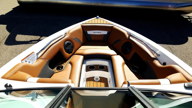 Slide: The Image of The image shows the bow of a 2017 Nautique Super Air Nautique 210 with brown leather seats. - 2