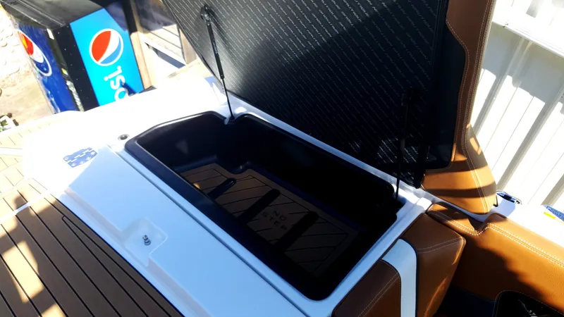 Slide: The Image of An open storage compartment on a boat with brown upholstery and a Pepsi machine in the background. - 12