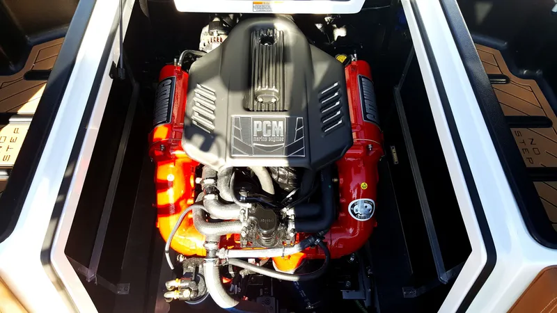 Slide: The Image of The engine compartment of a 2017 Nautique Super Air Nautique 210 features a powerful PCM engine with red accents. - 13