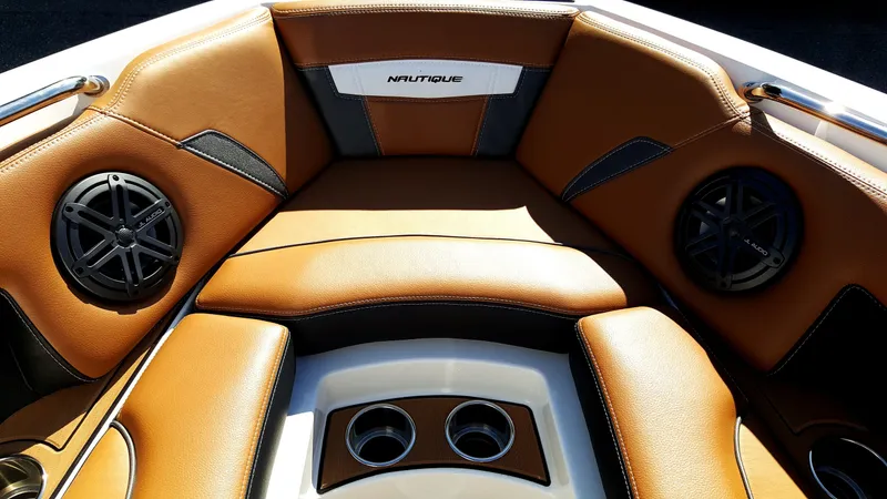 Slide: The Image of The image shows the bow area of a 2017 Nautique Super Air Nautique 210 with brown leather seats and speakers. - 18