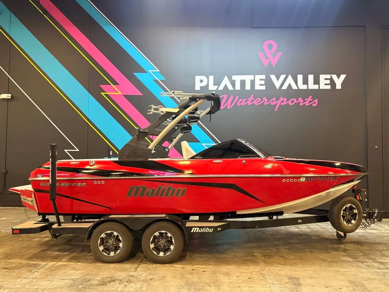 The Image of A red 2018 Malibu VLX 21 boat on a trailer in a showroom. - 1