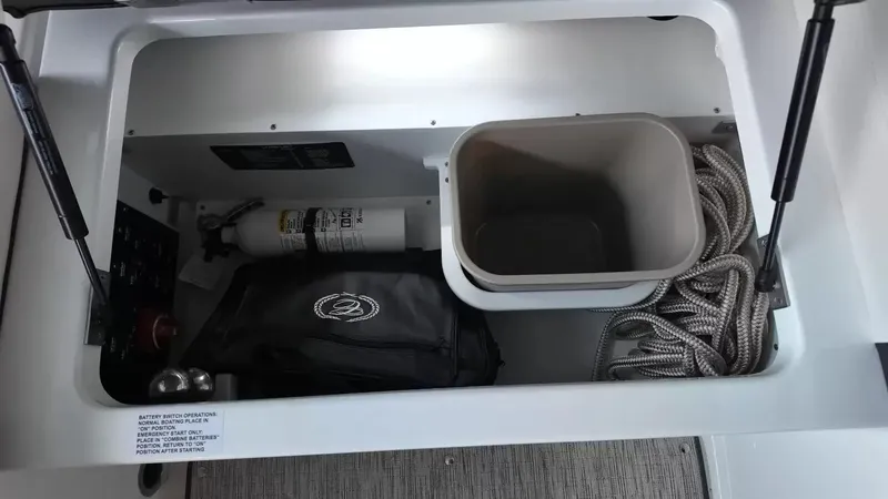 Slide: The Image of A storage compartment in the Cobalt R4 Surf boat with fire extinguisher, bag, rope, and container. - 36