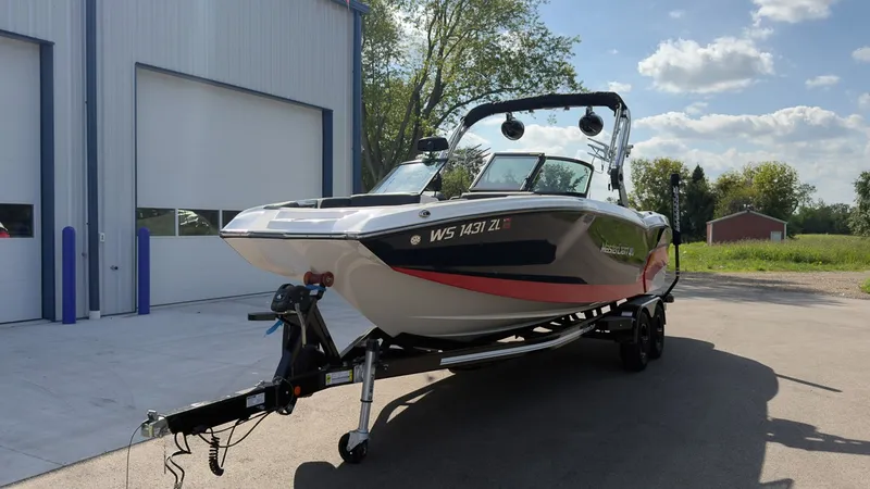 Slide: The Image of A 2021 MasterCraft NXT24 boat on a trailer in front of a building. - 2