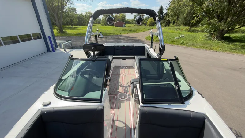 Slide: The Image of A 2021 MasterCraft NXT24 boat with an open deck, black interior, and a tower with speakers. - 20