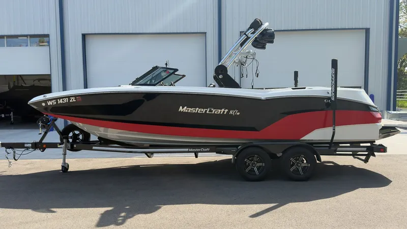 The Image of A 2021 MasterCraft NXT24 boat on a trailer in front of a warehouse. - 1