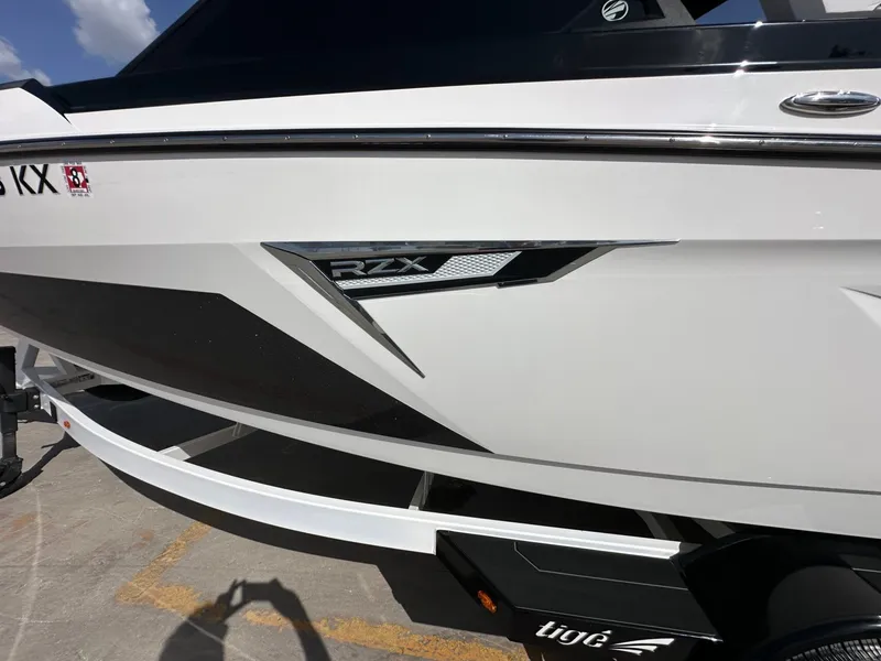 Slide: The Image of The image shows the side of a white 2024 Tigé 22RZX boat with sleek graphics. - 33