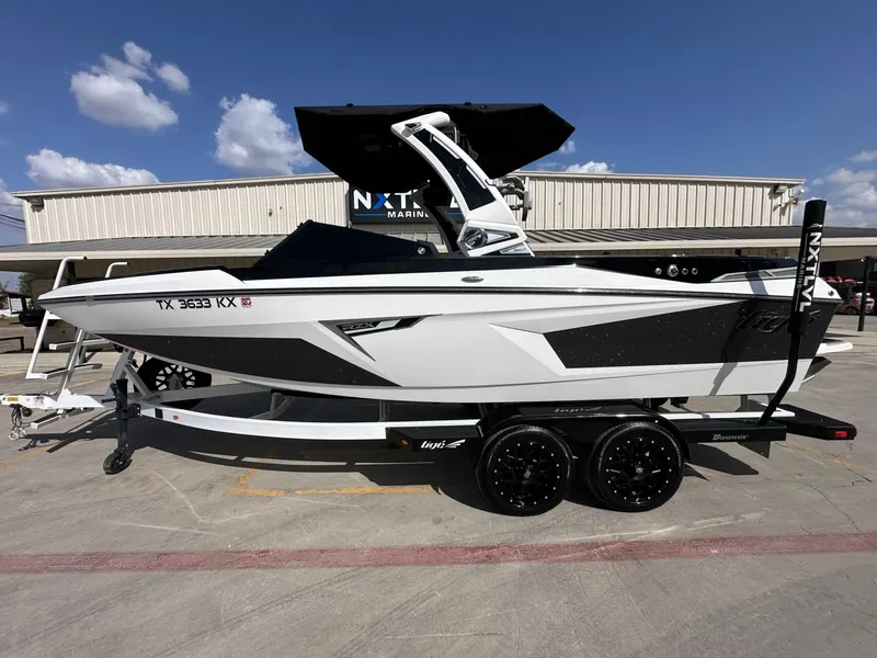 Slide: The Image of A white 2024 Tigé 22RZX boat on a trailer in front of a building. - 2