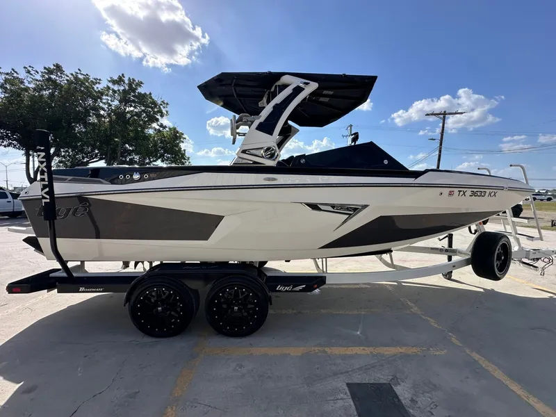 Slide: The Image of A 2024 Tigé 22RZX boat on a trailer, featuring a sleek design and tower, under a blue sky. - 7