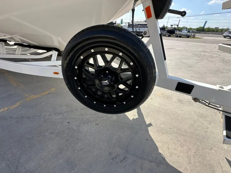 Slide: The Image of A black wheel with stylish rims on a boat trailer, parked in a lot. - 34