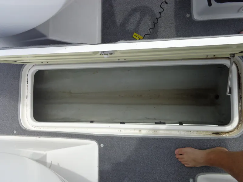 Slide: The Image of An open storage compartment on a boat with gray flooring and a bare foot visible. - 35