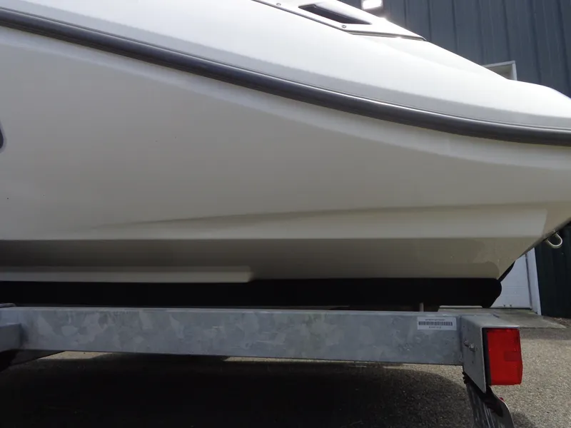 Slide: The Image of A white boat, partially on a trailer, parked in front of a building. - 44