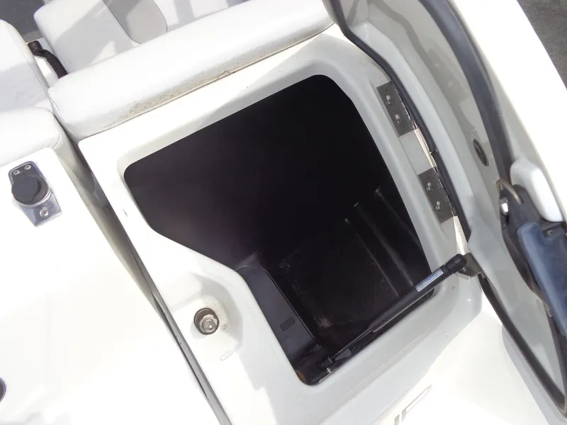 Slide: The Image of An open storage compartment on a white boat with hinges and a latch. - 30