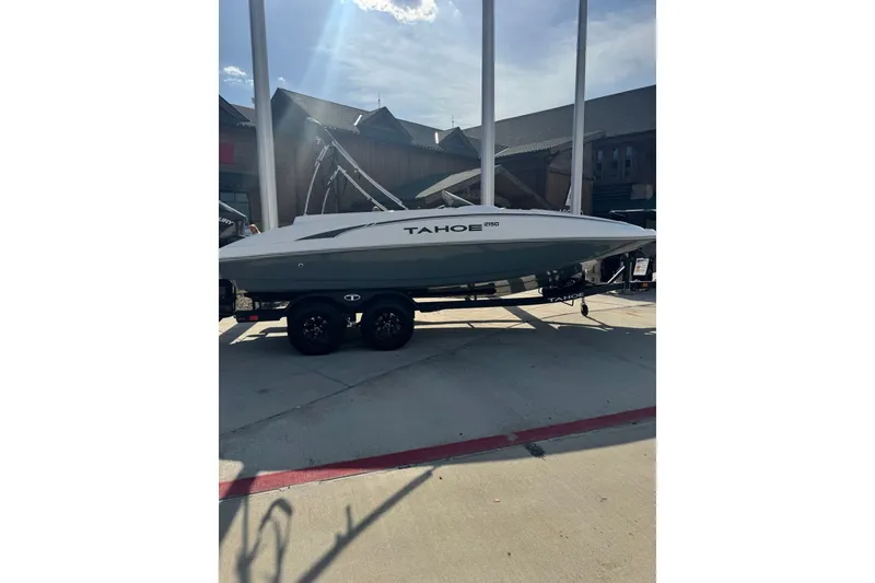 The Image of 2027 Tahoe 2150 boat on trailer, parked outdoors under bright sunlight. - 0