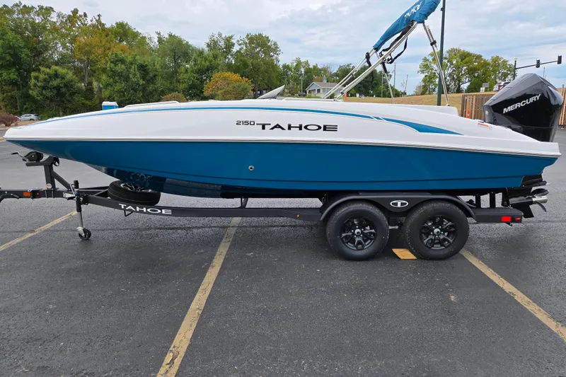 Slide: The Image of 2027 Tahoe 2150 boat on trailer, blue and white design, parked outdoors. - 4