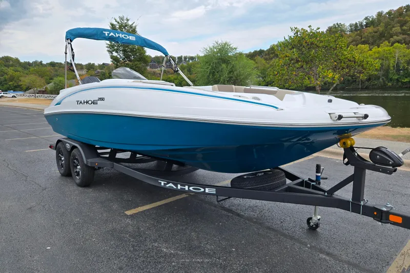 Slide: The Image of 2027 Tahoe 2150 boat on trailer, parked near a scenic river with lush greenery. - 1