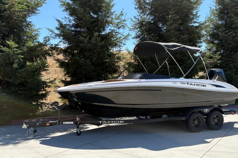 Slide: The Image of 2027 Tahoe 210 S boat on trailer, parked outdoors near trees. - 4