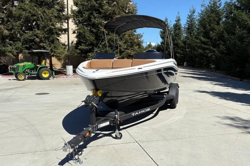 Slide: The Image of 2027 Tahoe 210 S boat on trailer, parked outdoors with trees in background. - 8