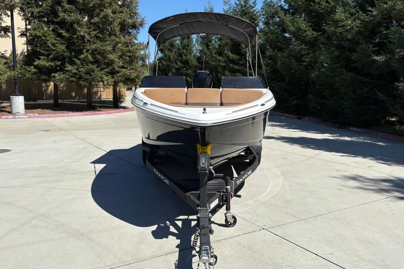 Slide: The Image of 2027 Tahoe 210 S boat on trailer, parked outdoors with trees in background. - 7