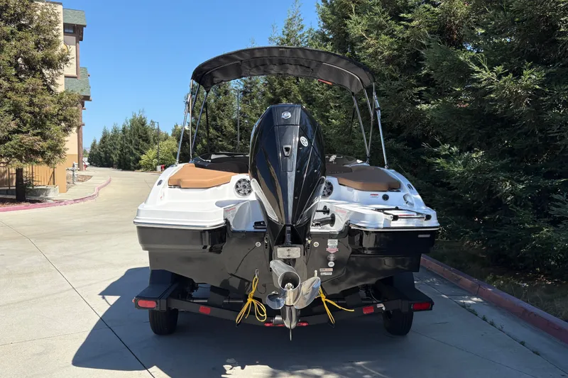 Slide: The Image of 2027 Tahoe 210 S boat with outboard motor on trailer, parked near trees. - 9